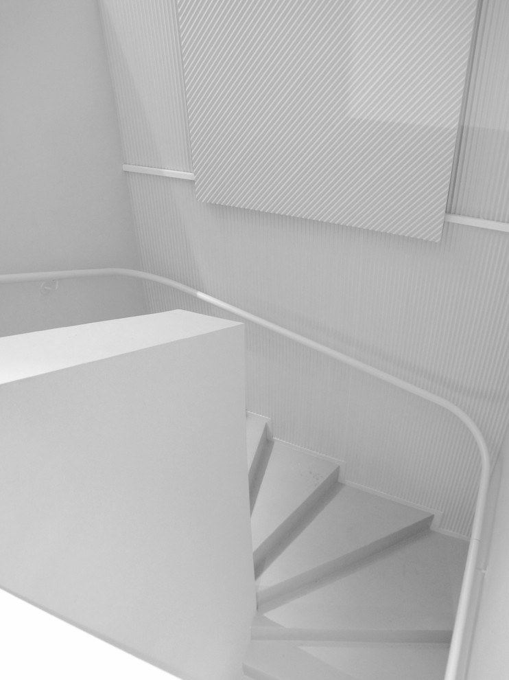 Foto de escalera curva clásica de tamaño medio con escalones de hormigón, contrahuellas de hormigón y barandilla de metal