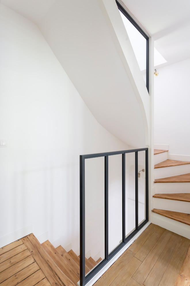 Modelo de escalera curva actual de tamaño medio con escalones de madera, contrahuellas de madera y barandilla de metal
