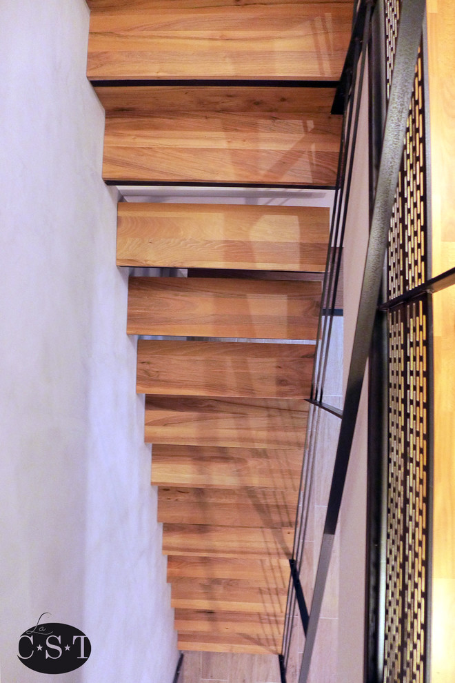 Cette image montre un grand escalier droit urbain avec des marches en bois et des contremarches en métal.