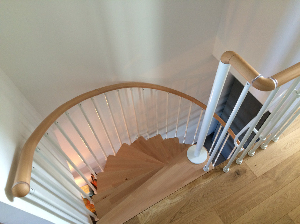 Cette photo montre un escalier hélicoïdal tendance de taille moyenne avec des marches en bois et un garde-corps en métal.
