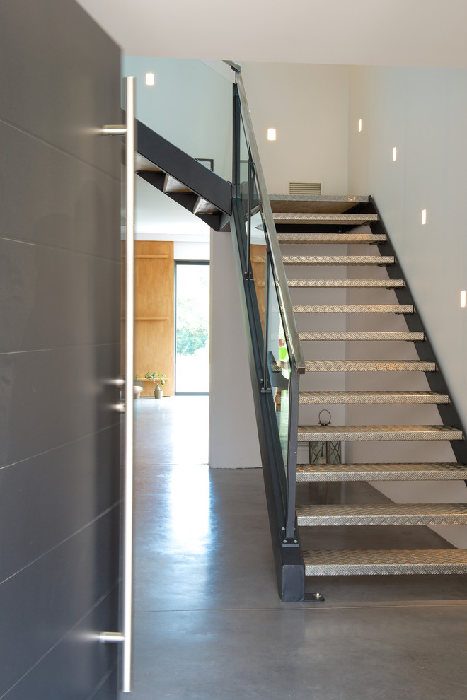 Ejemplo de escalera curva actual con escalones de metal y barandilla de vidrio