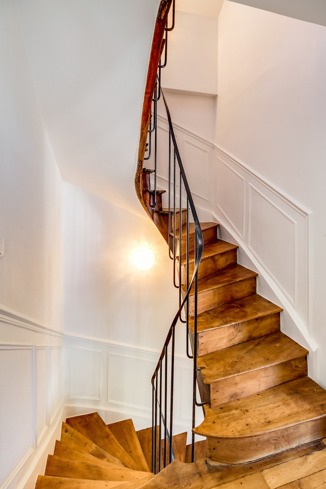 Réalisation d'un escalier courbe design de taille moyenne avec un garde-corps en métal, des marches en bois et des contremarches en bois.