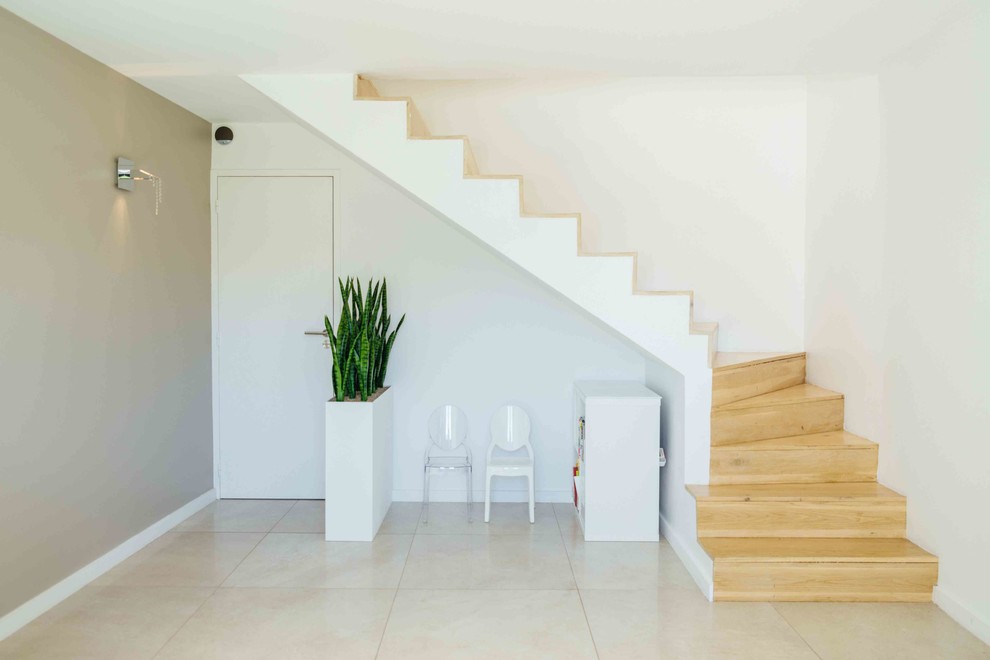 На фото: угловая лестница в средиземноморском стиле с крашенными деревянными ступенями и крашенными деревянными подступенками с