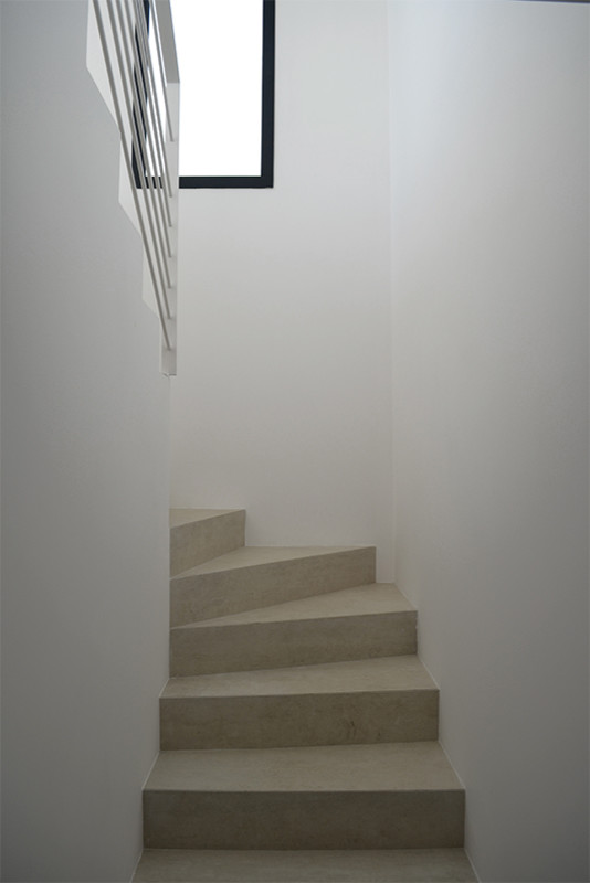 Ejemplo de escalera en U minimalista de tamaño medio con escalones con baldosas, contrahuellas con baldosas y/o azulejos y barandilla de metal
