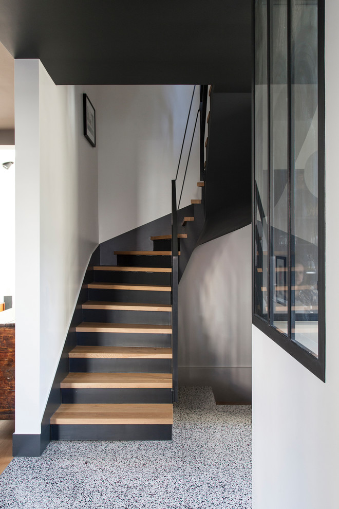 На фото: большая п-образная лестница в современном стиле с деревянными ступенями, крашенными деревянными подступенками и металлическими перилами с