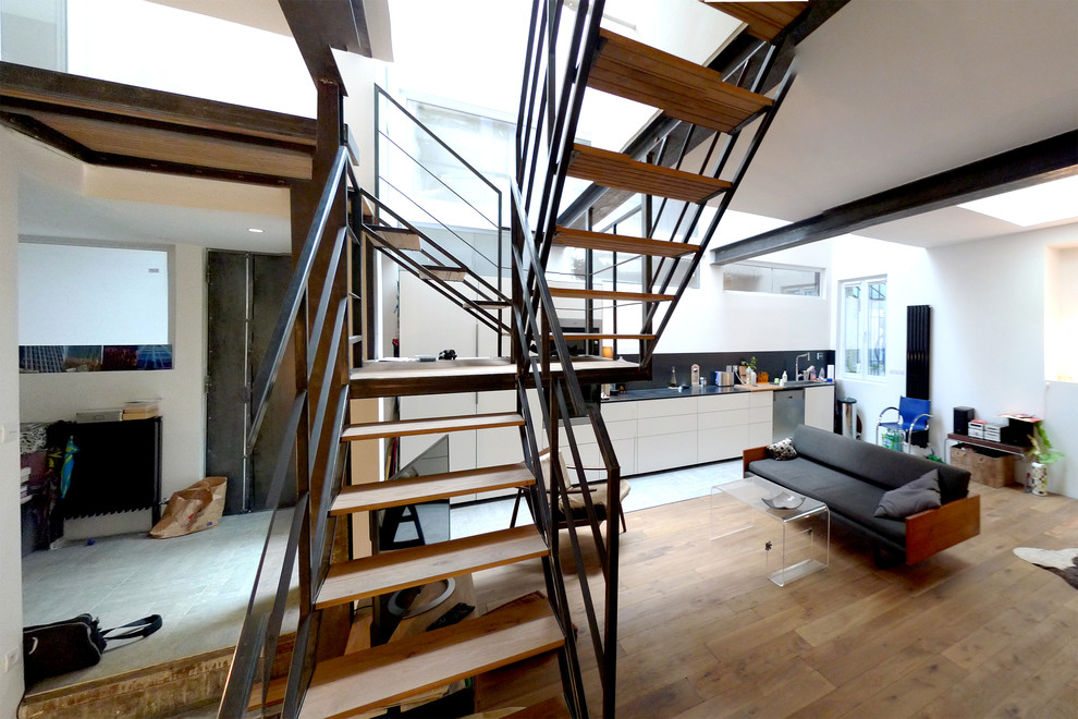 Photo of a large industrial wood u-shaped staircase in Paris with open risers.