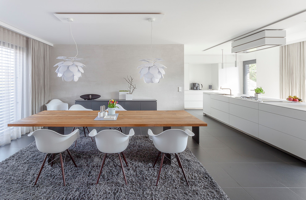 Modern inredning av en mellanstor matplats med öppen planlösning, med grå väggar, klinkergolv i keramik och svart golv