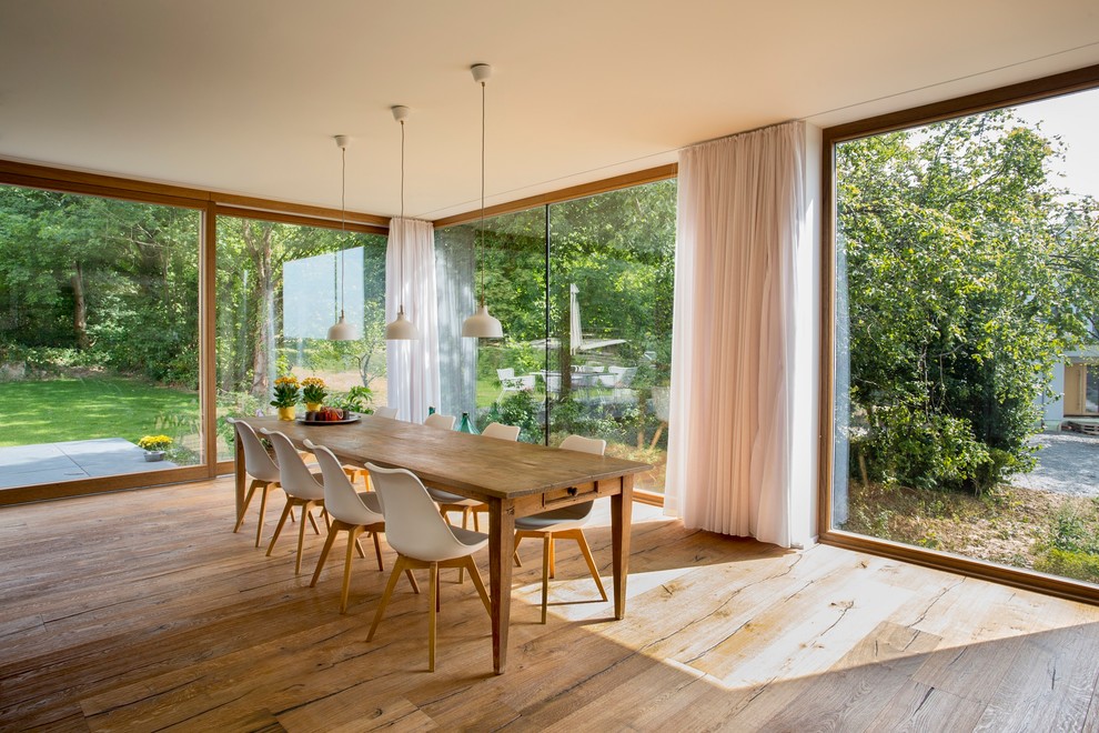 Immagine di un'ampia sala da pranzo aperta verso il soggiorno contemporanea con pavimento in legno massello medio