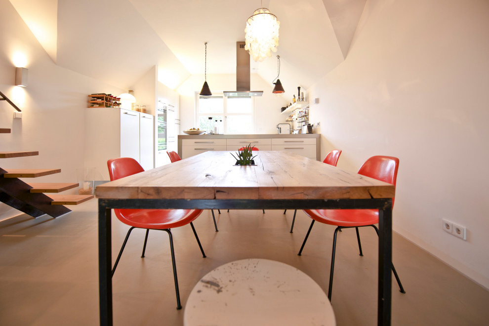 На фото: столовая в современном стиле с белыми стенами и бетонным полом с