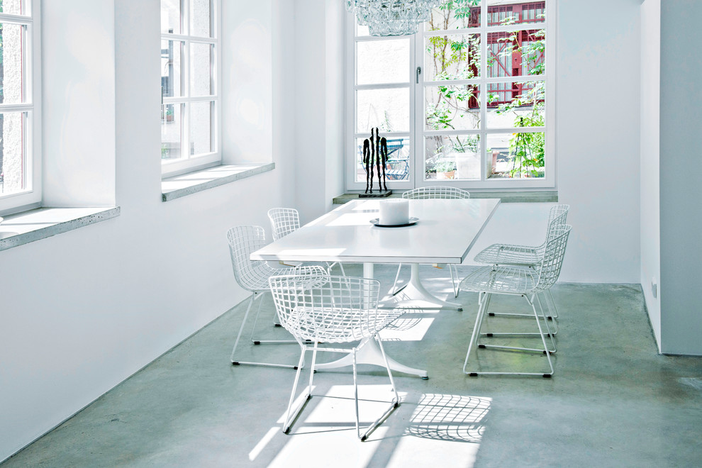 Inspiration for a large urban dining room in Munich with white walls and concrete flooring.