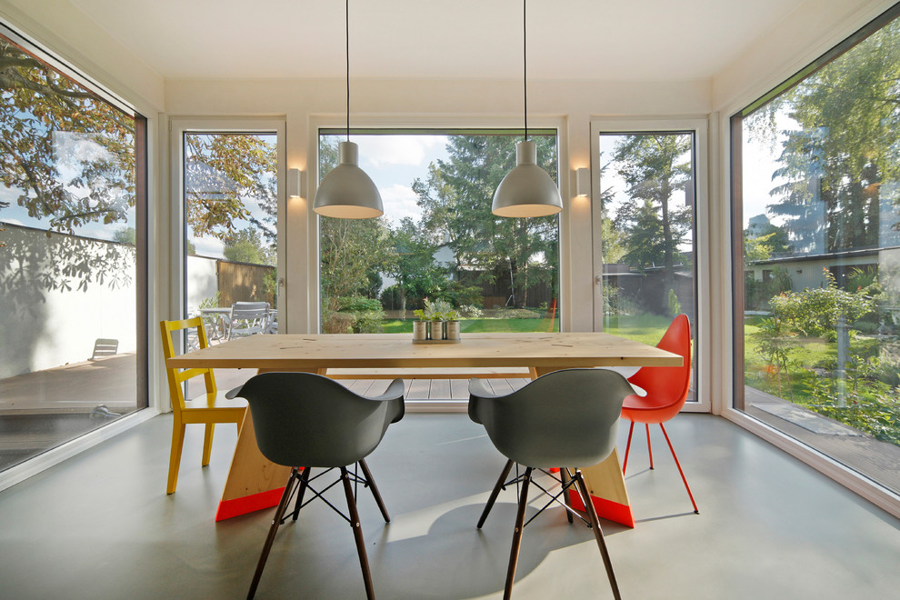 Esempio di una sala da pranzo aperta verso la cucina contemporanea di medie dimensioni con pareti bianche e pavimento in cemento