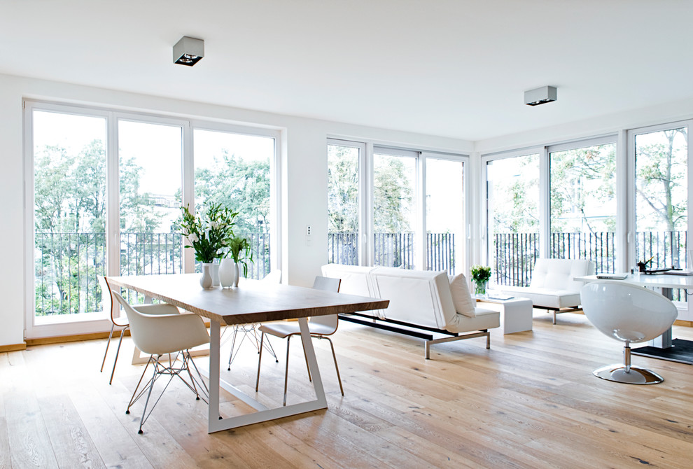 Réalisation d'une grande salle à manger ouverte sur le salon design avec un mur blanc et un sol en bois brun.