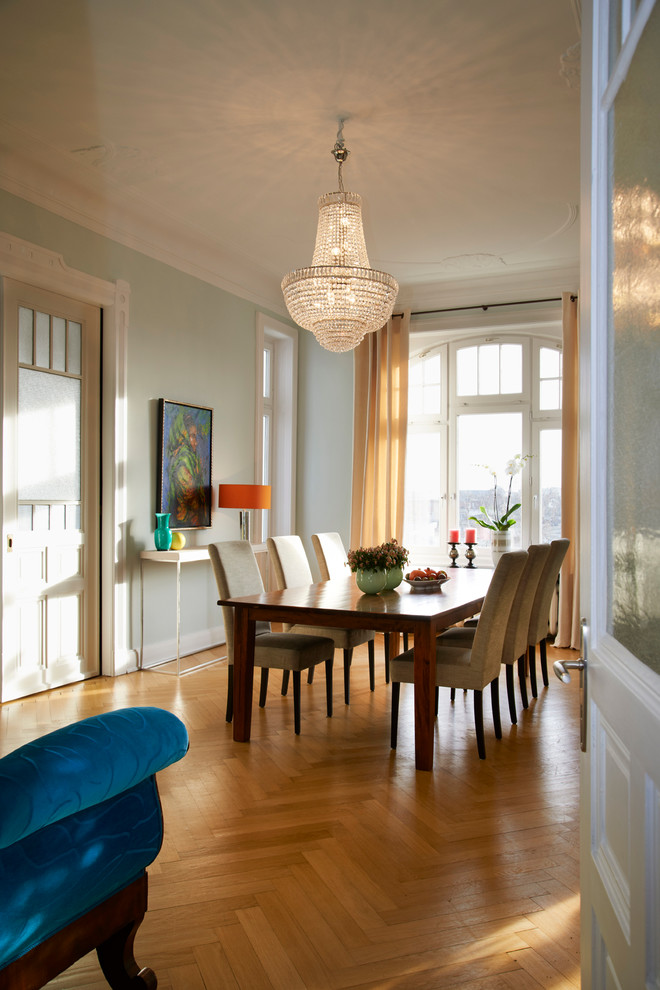 Cette image montre une salle à manger design avec un mur vert et un sol en bois brun.