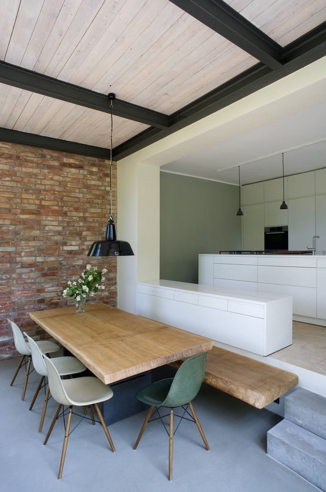 На фото: кухня-столовая среднего размера в современном стиле с красными стенами и бетонным полом без камина с