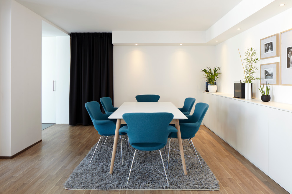 Idée de décoration pour une salle à manger ouverte sur le salon design de taille moyenne avec un mur blanc et parquet clair.