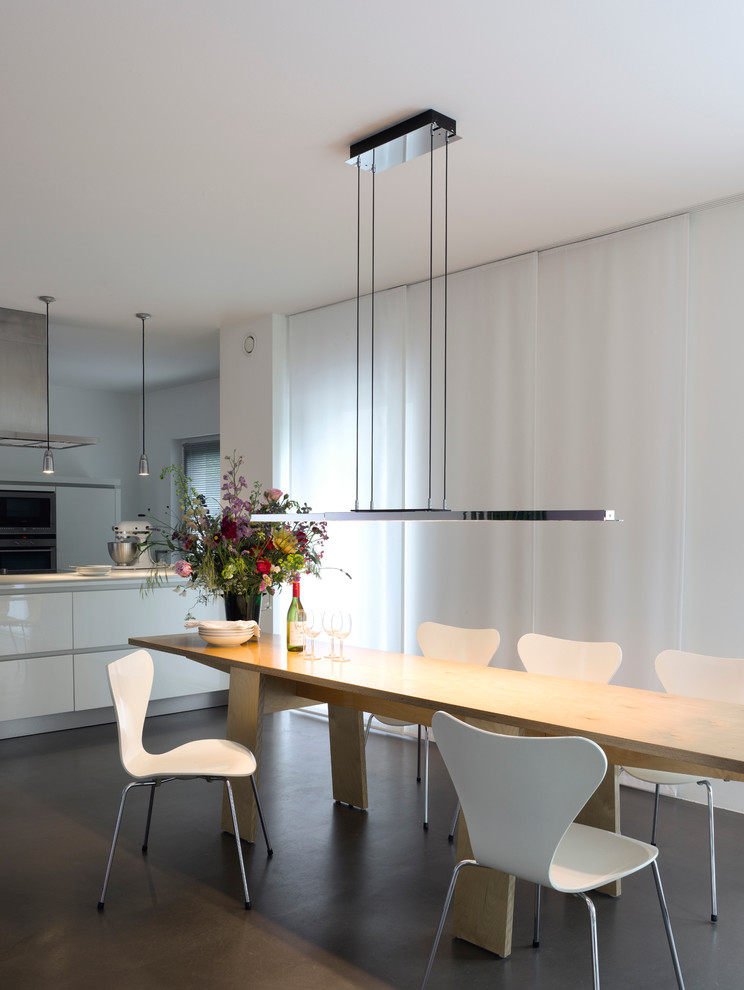 Cette image montre une salle à manger ouverte sur la cuisine design avec un mur blanc.