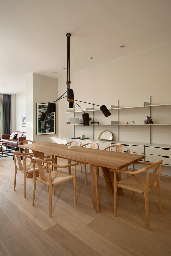 Foto di una sala da pranzo aperta verso il soggiorno scandinava con pareti beige e parquet chiaro