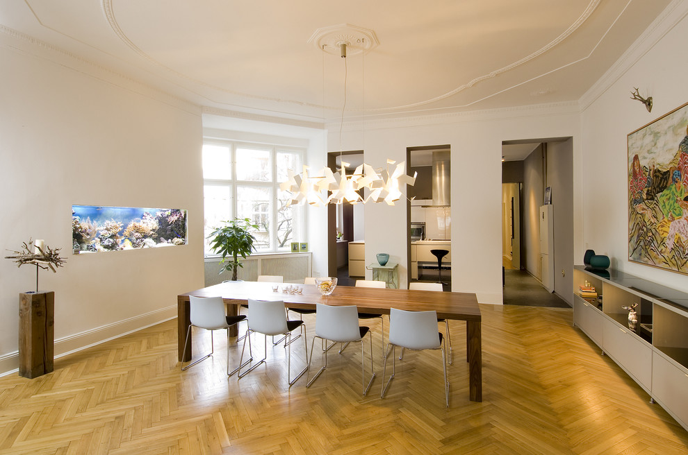 Immagine di una grande sala da pranzo aperta verso il soggiorno minimal con pareti bianche e pavimento in legno massello medio