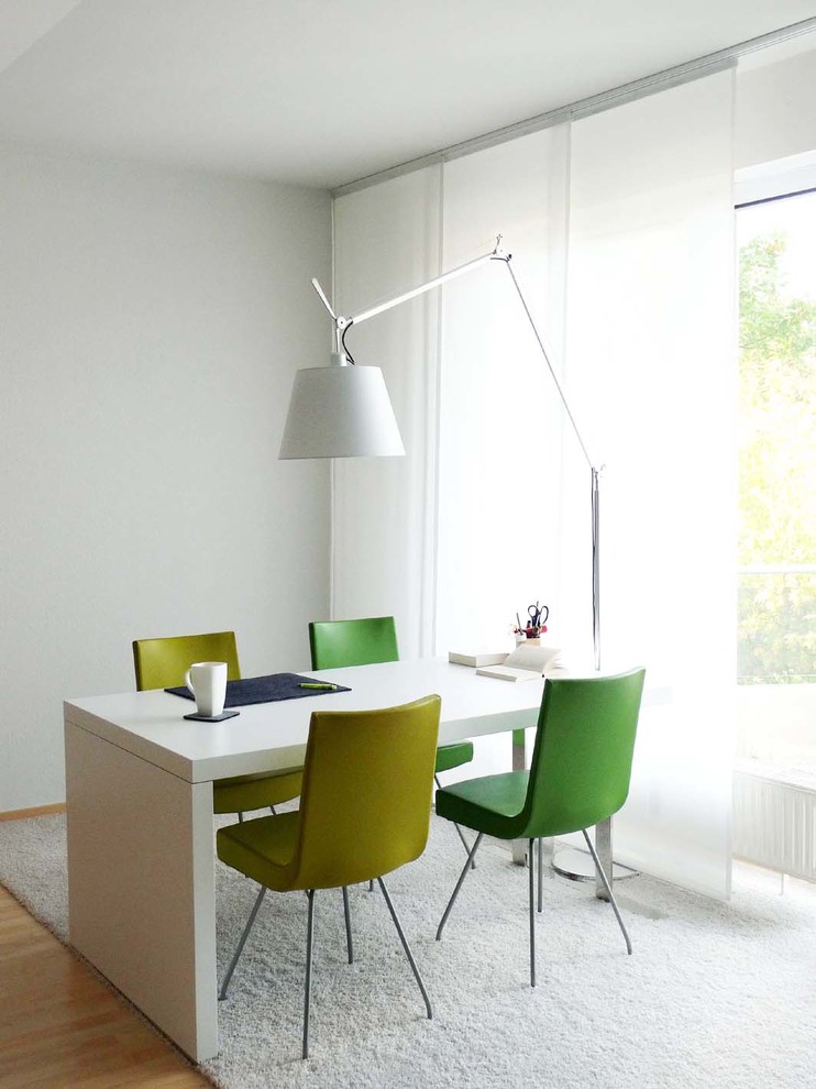 Imagen de comedor actual pequeño con paredes blancas y suelo de madera en tonos medios