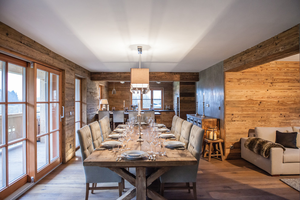 Idées déco pour une salle à manger ouverte sur la cuisine montagne avec un mur marron, un sol en bois brun et un sol marron.