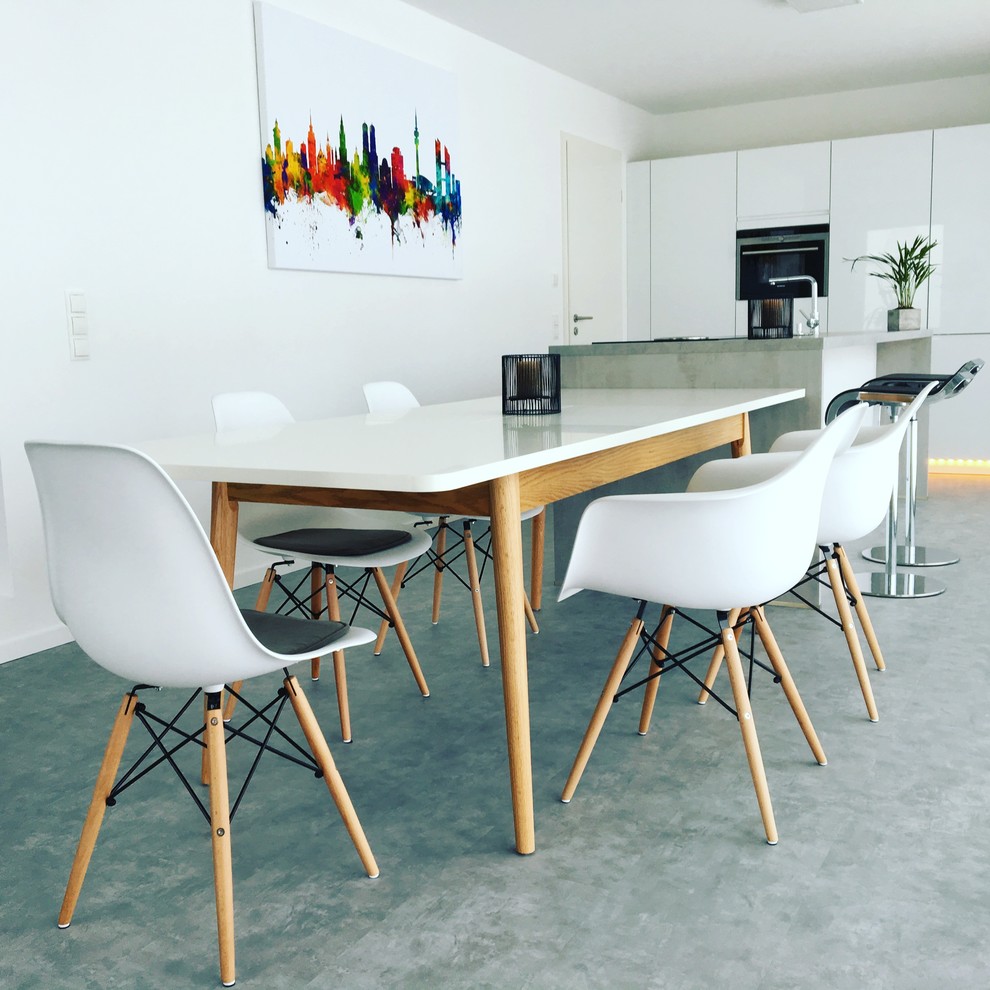 Ispirazione per una sala da pranzo aperta verso la cucina minimalista di medie dimensioni con pareti bianche, pavimento in cemento, nessun camino e pavimento grigio