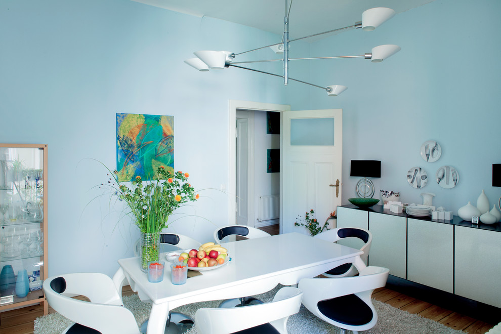 Idée de décoration pour une salle à manger bohème avec un mur bleu et un sol en bois brun.