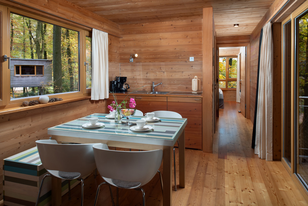Réalisation d'une petite salle à manger ouverte sur la cuisine chalet en bois avec un mur marron, un sol en bois brun et un sol marron.