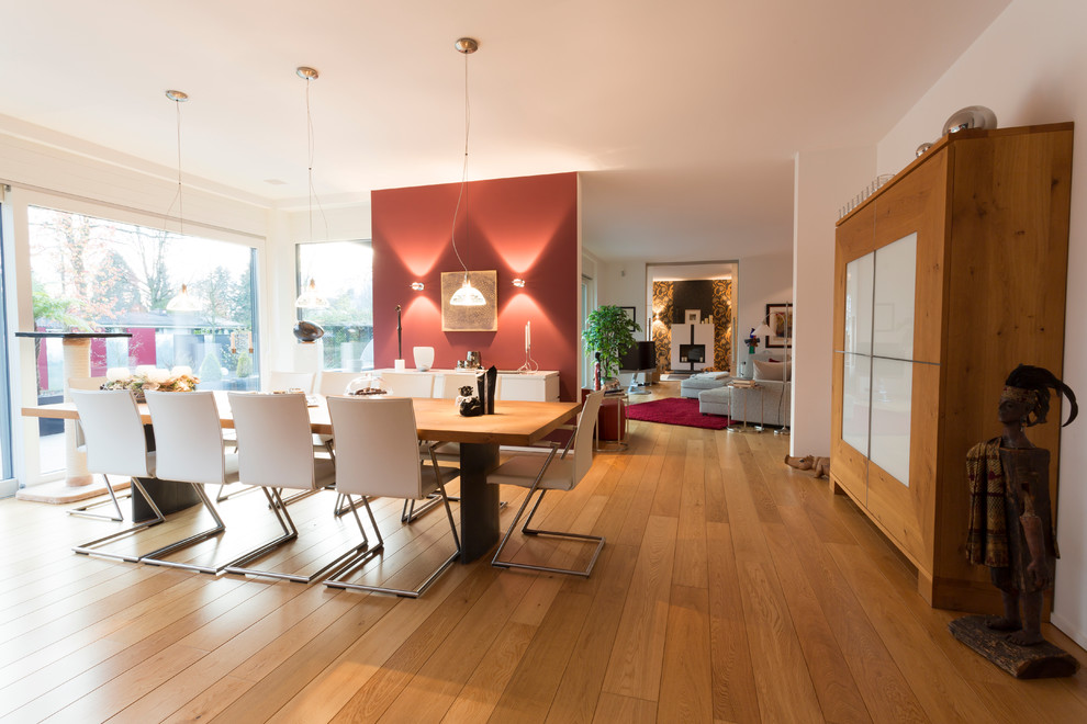 Offenes, Großes Modernes Esszimmer mit roter Wandfarbe, braunem Holzboden und braunem Boden in Düsseldorf