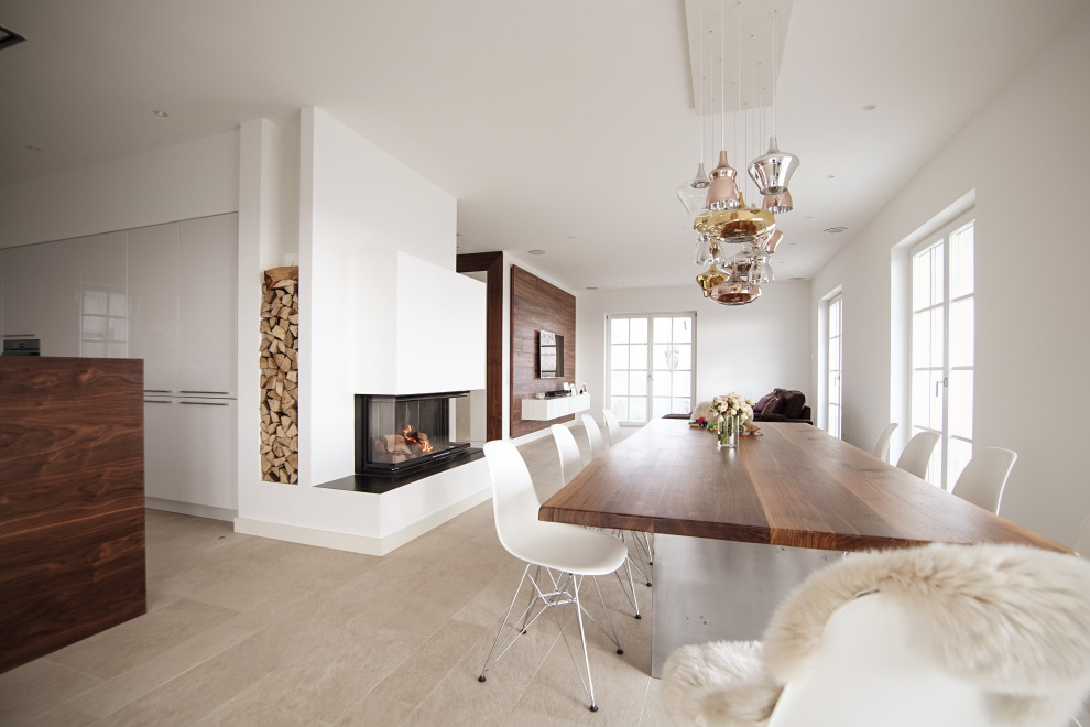 Imagen de comedor de cocina grande con paredes blancas, suelo de pizarra, chimenea de doble cara, marco de chimenea de yeso y suelo beige