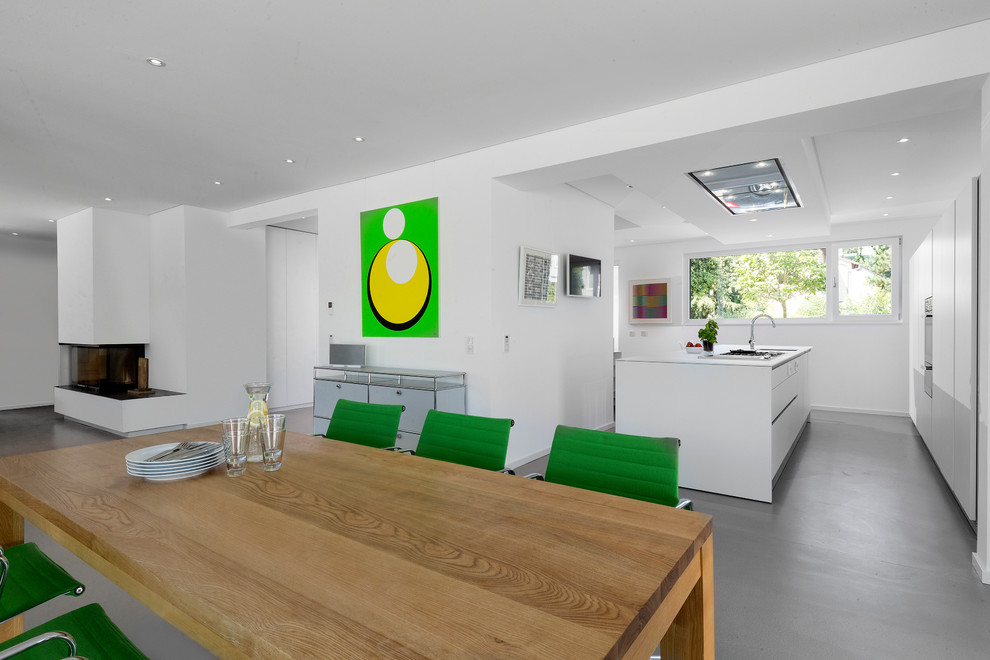 Idée de décoration pour une salle à manger ouverte sur le salon design de taille moyenne avec un mur blanc, un manteau de cheminée en plâtre et une cheminée standard.