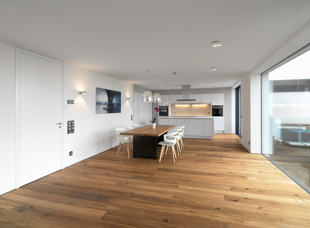 Esempio di una grande sala da pranzo minimal con pareti bianche e pavimento in legno massello medio