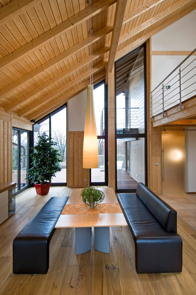 Cette photo montre une grande salle à manger ouverte sur le salon tendance avec un mur blanc et un sol en bois brun.