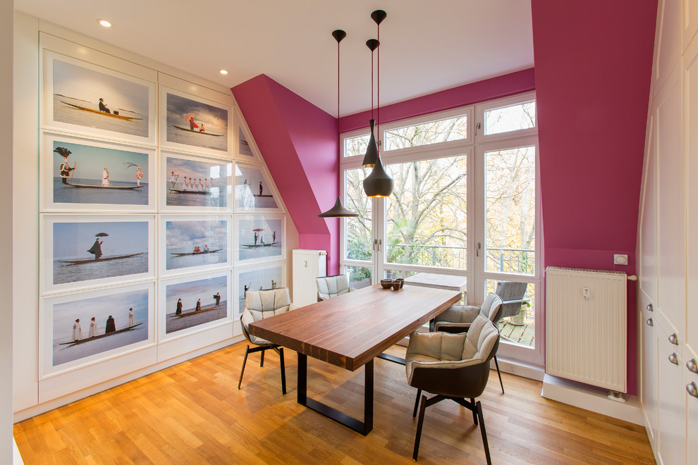 Kleines Stilmix Esszimmer ohne Kamin mit braunem Holzboden, rosa Wandfarbe und braunem Boden in Berlin
