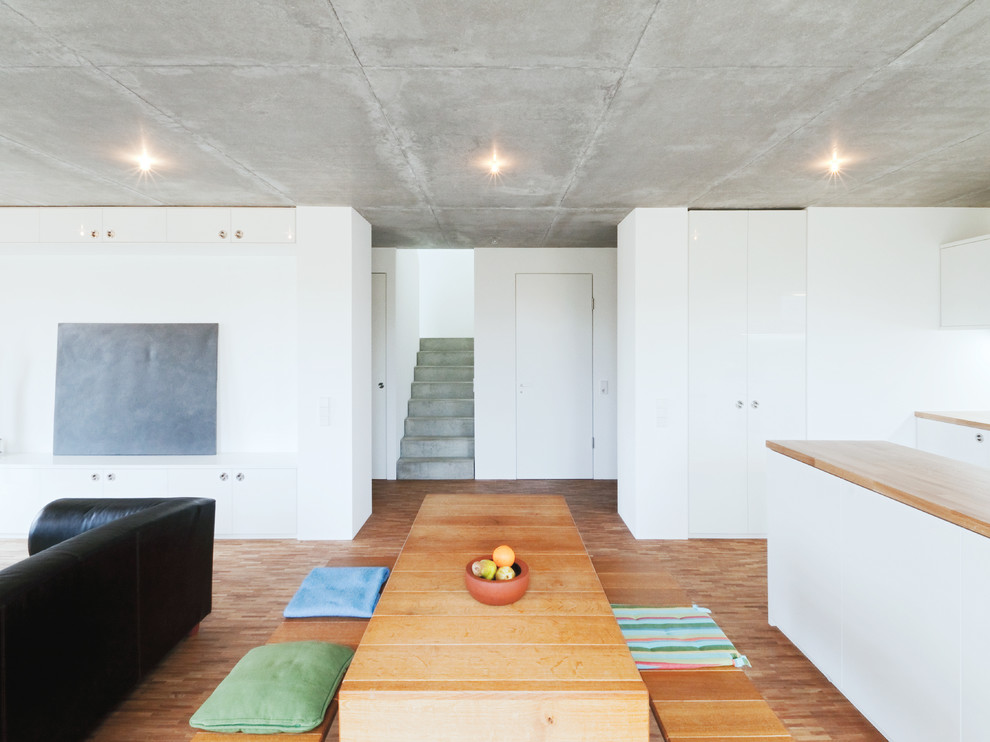 Foto de comedor minimalista de tamaño medio abierto con paredes blancas, suelo de madera en tonos medios y suelo marrón