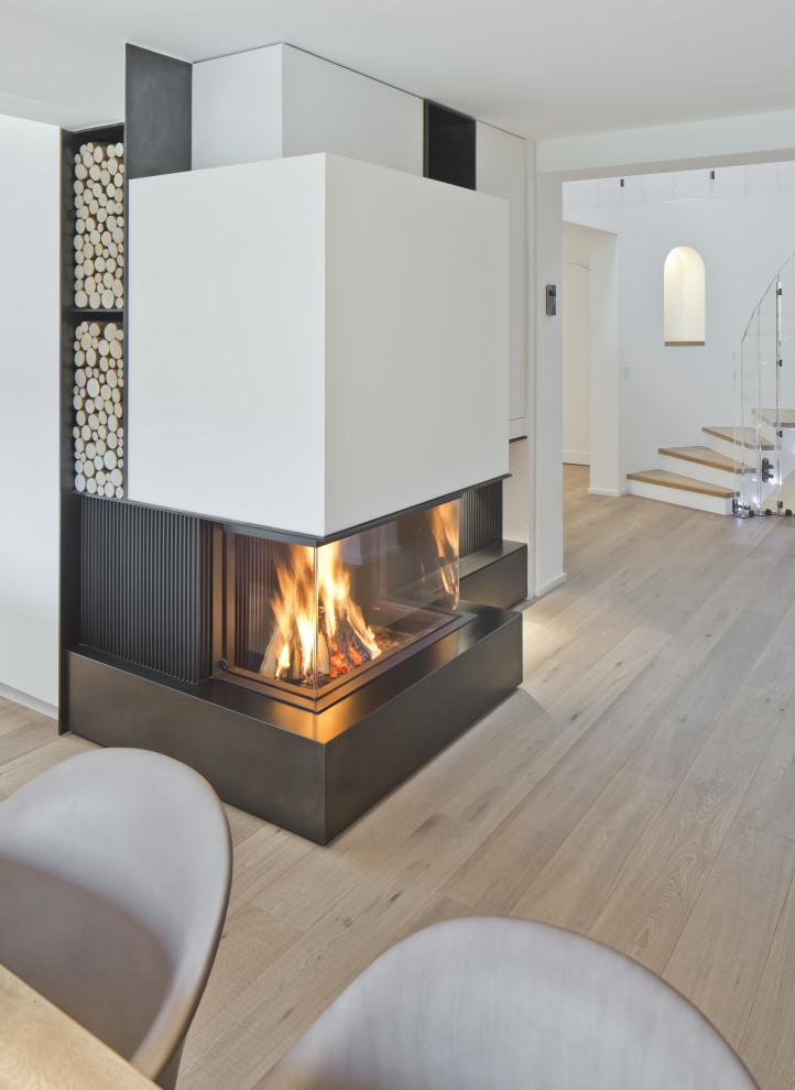 Geräumige Moderne Wohnküche mit weißer Wandfarbe, braunem Holzboden, Kaminofen, verputzter Kaminumrandung und beigem Boden in München