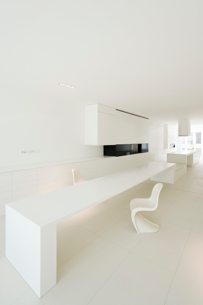Réalisation d'une très grande salle à manger ouverte sur la cuisine minimaliste avec un sol blanc, un mur blanc et aucune cheminée.