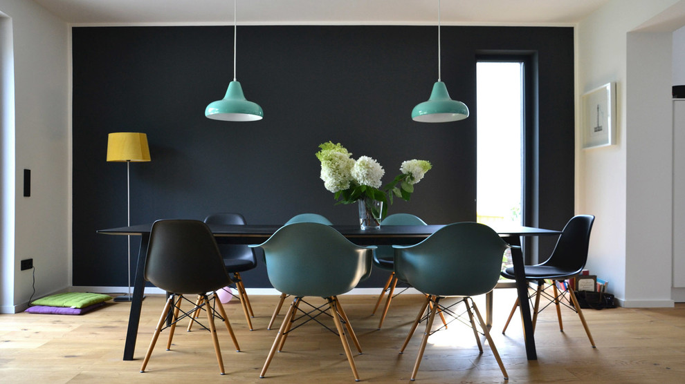 Inspiration for a medium sized midcentury open plan dining room in Cologne with black walls, light hardwood flooring and feature lighting.