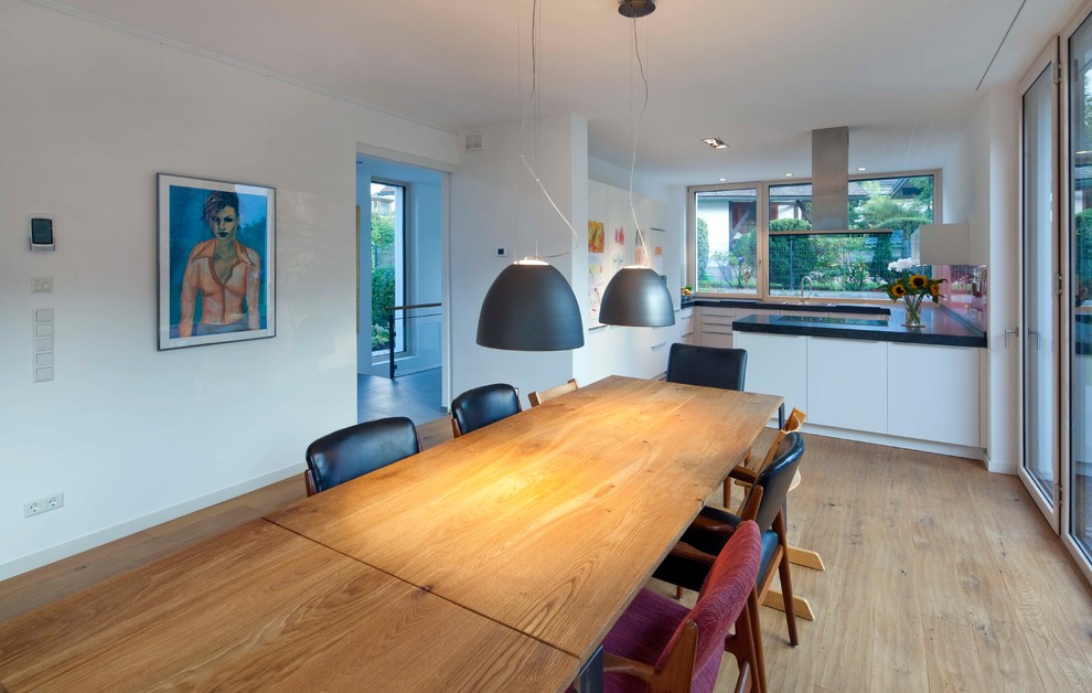 Mittelgroße Moderne Wohnküche ohne Kamin mit weißer Wandfarbe, braunem Holzboden und braunem Boden in München