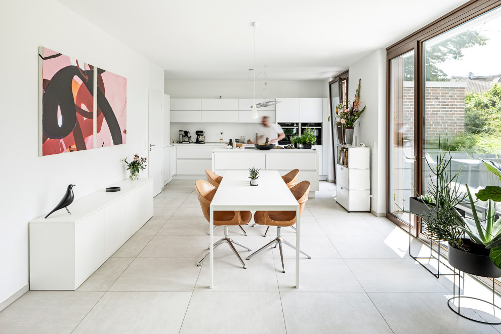 На фото: кухня-столовая в стиле модернизм с белыми стенами и серым полом с