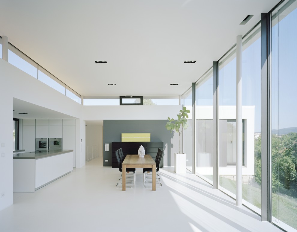 Inspiration pour une grande salle à manger ouverte sur la cuisine minimaliste avec un mur blanc.