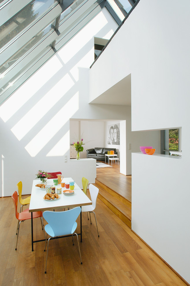 Источник вдохновения для домашнего уюта: гостиная-столовая среднего размера в современном стиле с белыми стенами, паркетным полом среднего тона и коричневым полом без камина