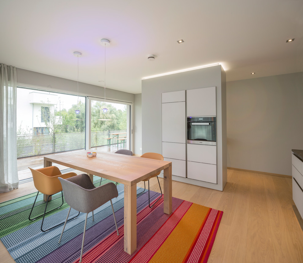 Moderne Wohnküche mit hellem Holzboden, grauer Wandfarbe und braunem Boden in Nürnberg