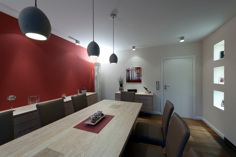 Cette photo montre une salle à manger tendance avec un mur rouge.