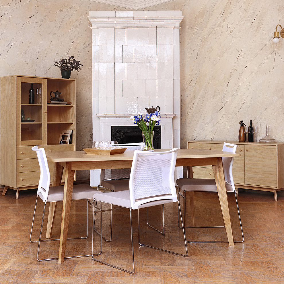 Foto di una sala da pranzo minimalista chiusa e di medie dimensioni con pareti beige, pavimento in legno massello medio, stufa a legna, cornice del camino piastrellata e pavimento marrone