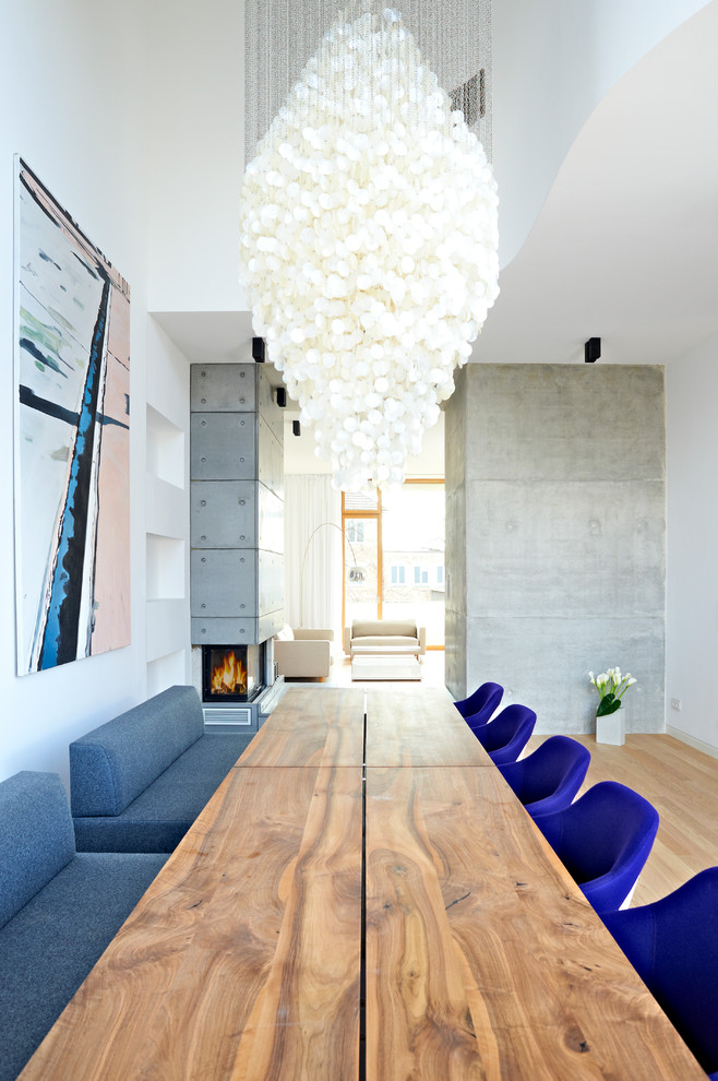 ハンブルクにある広いコンテンポラリースタイルのおしゃれなLDK (白い壁、淡色無垢フローリング、コンクリートの暖炉まわり、コーナー設置型暖炉) の写真