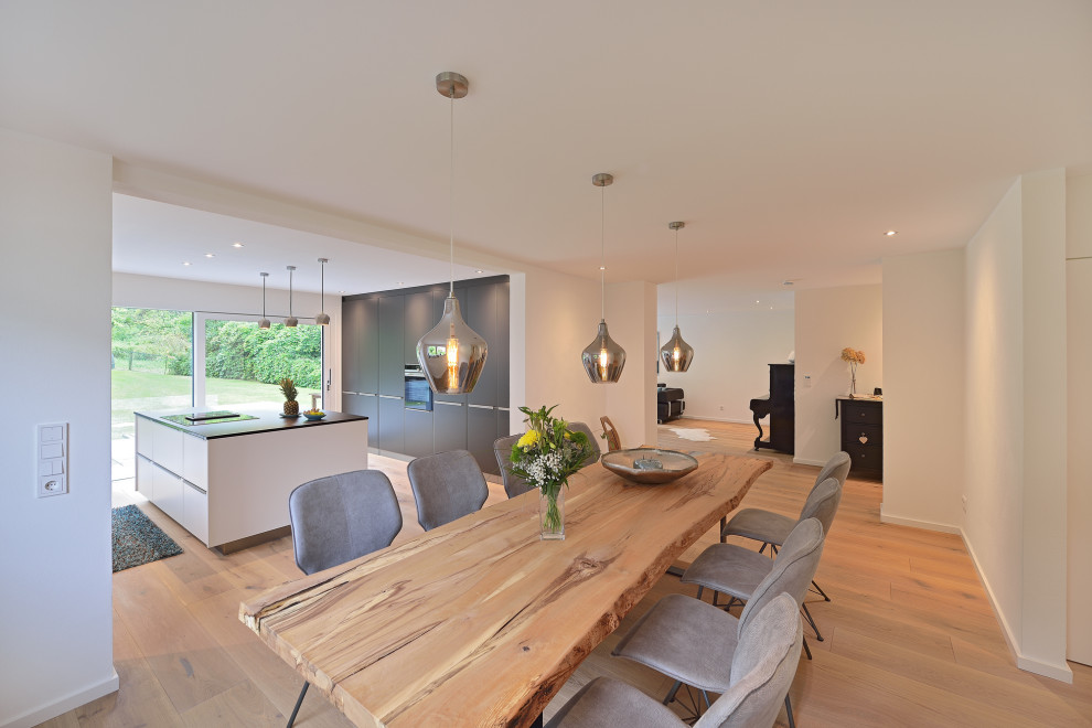 Foto di una sala da pranzo aperta verso il soggiorno minimalista di medie dimensioni con pareti bianche e pavimento in legno massello medio