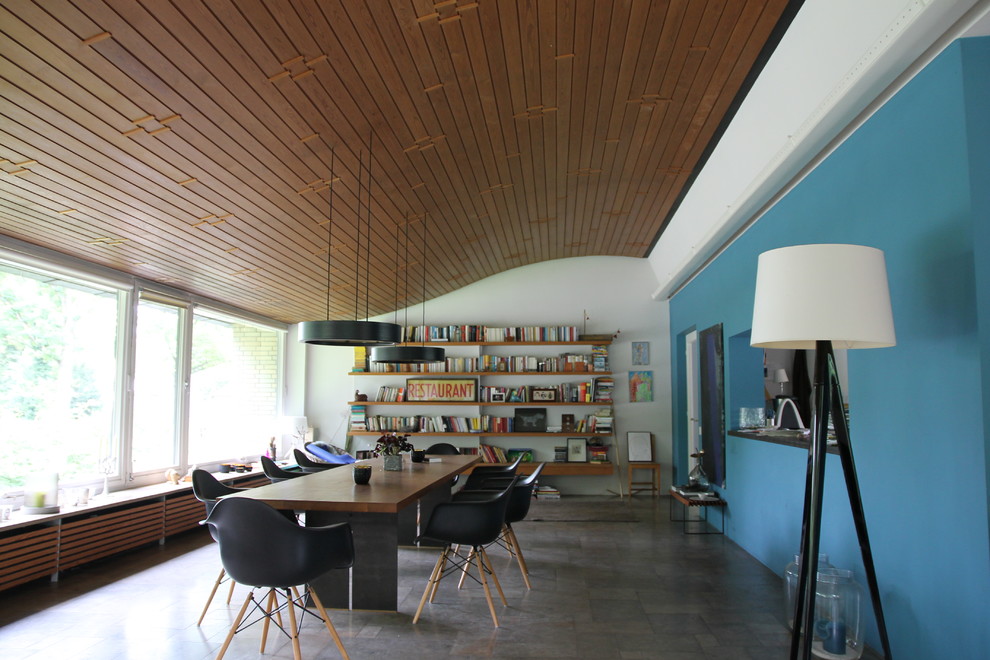 Réalisation d'une grande salle à manger ouverte sur le salon bohème avec un mur bleu, un sol en carrelage de céramique, une cheminée standard, un manteau de cheminée en pierre et un sol marron.