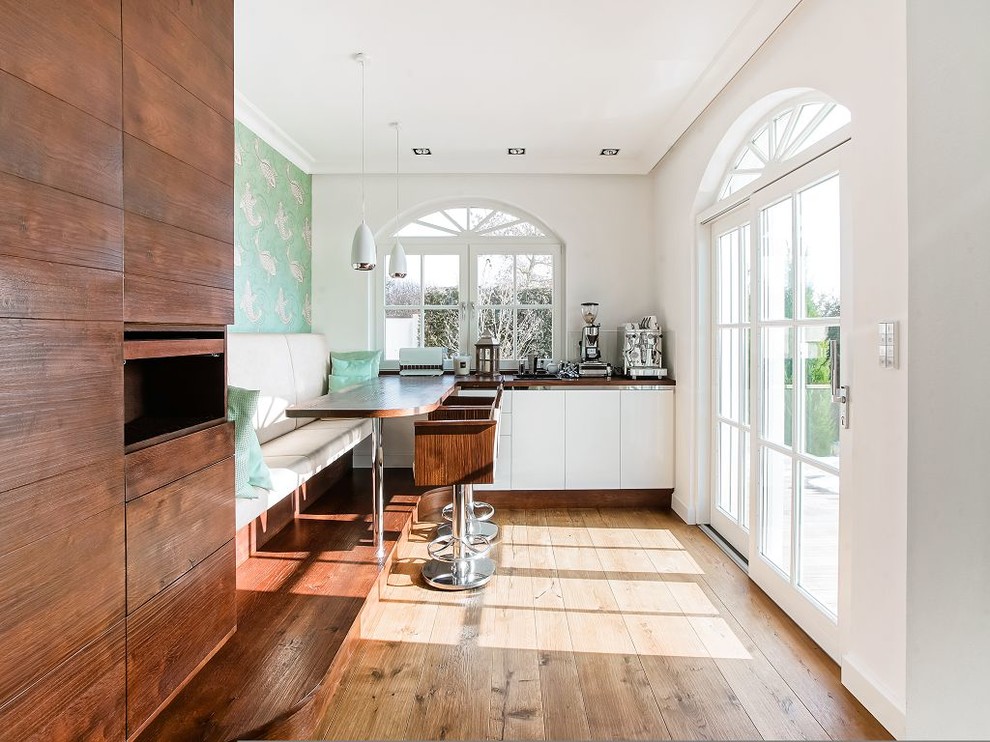 Ispirazione per una sala da pranzo aperta verso la cucina minimal di medie dimensioni con pareti bianche e pavimento in legno massello medio