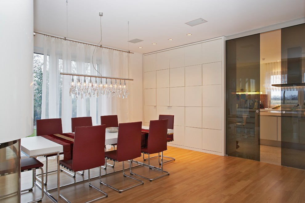 Foto di una sala da pranzo aperta verso il soggiorno design di medie dimensioni con pareti bianche, parquet chiaro e pavimento marrone
