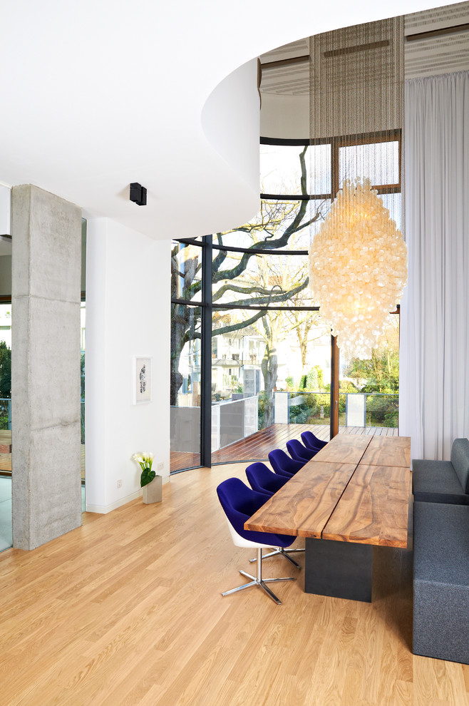 This is an example of a large contemporary open plan dining room in Hamburg with white walls and light hardwood flooring.